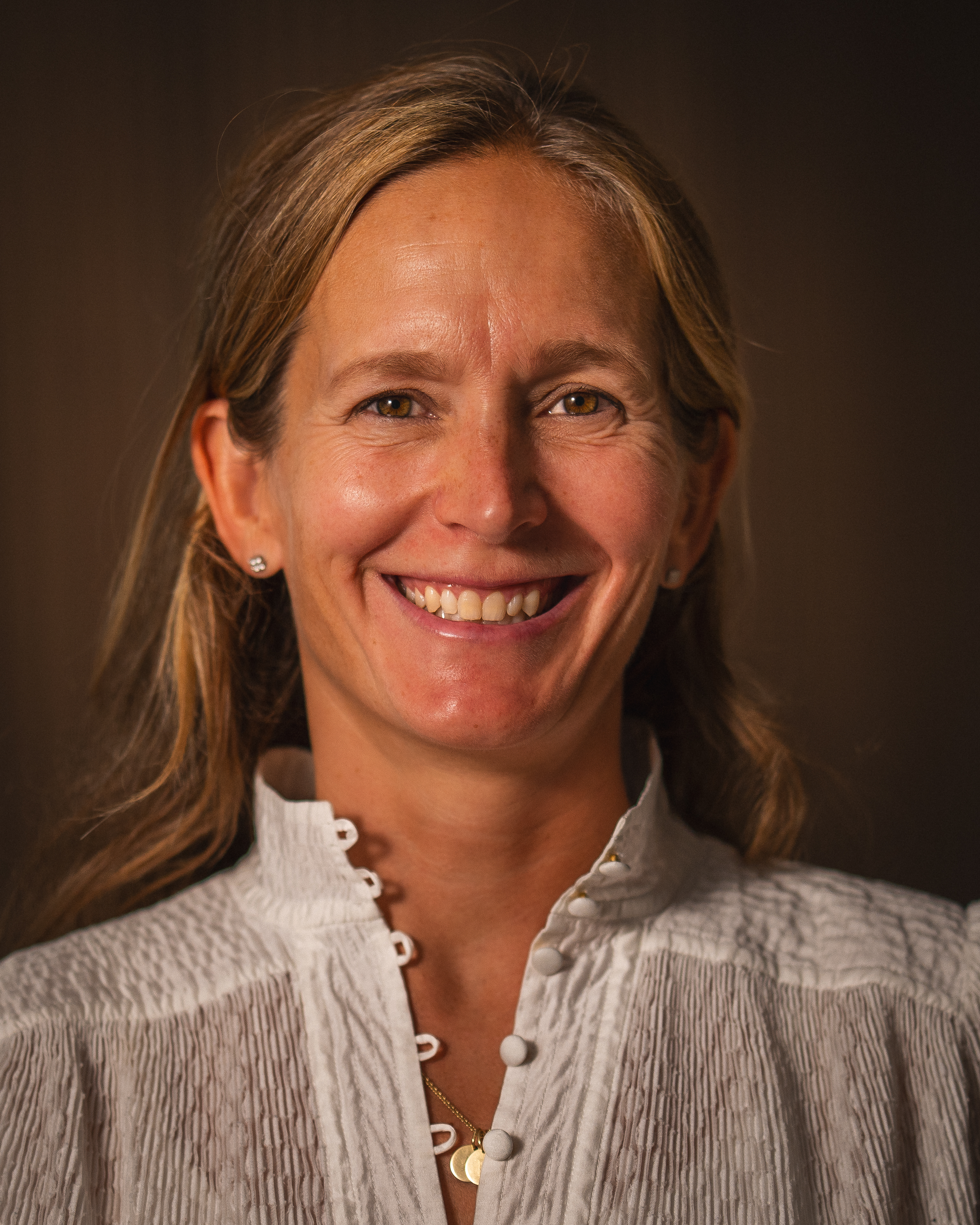 Portrett av Helle Aanesen, daglig leder i Aktiv mot kreft, med smilende ansikt i skjorte med knapper.