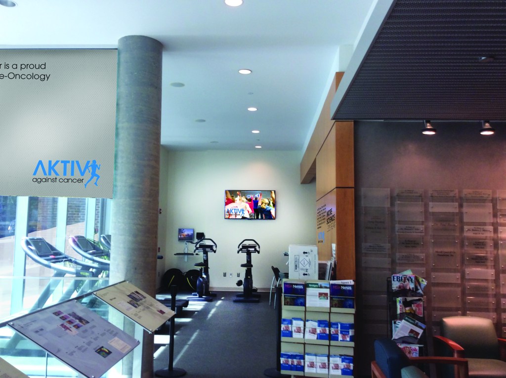 Innvendig bilde av treningssenteret med AKTIV mot kreft-logo, treningsapparater og informasjonsmateriell.